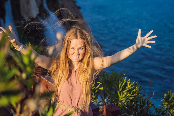 Woman with crazy hair on the background of Duden waterfall in Antalya. Famous places of Turkey. Lower Duden Falls drop off a rocky cliff falling from about 40 m into the Mediterranean Sea in amazing