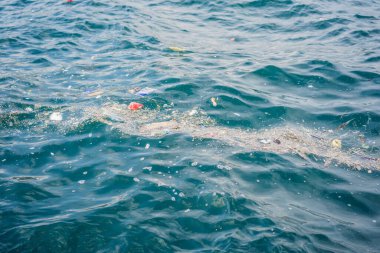 Plastik ve diğer döküntüler mavi suda yüzer. Plastik çöpler denizleri ve okyanusu kirletiyor..