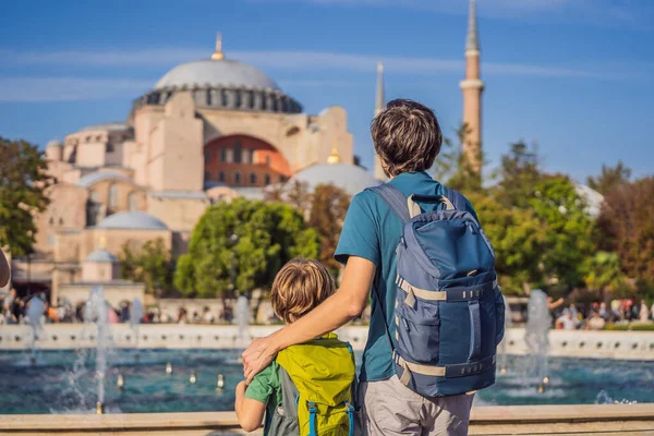 Father and son Tourists enjoy beautiful view on Hagia Sophia Cathedral, famous islamic Landmark mosque, Travel to Istanbul, Turkey. Traveling with kids concept. Sunny day architecture and Hagia Sophia
