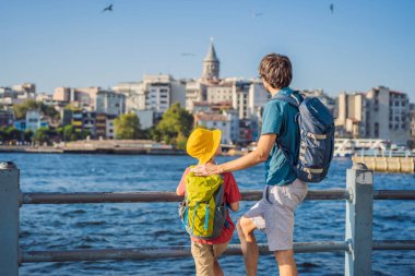Baba ve oğul turistler Türkiye 'de İstanbul şehrinin ufuk çizgisinin keyfini çıkarırken, Beyoğlu' nda Galata kulesinin tepesinde eski evler, Altın Boynuz manzarası.
