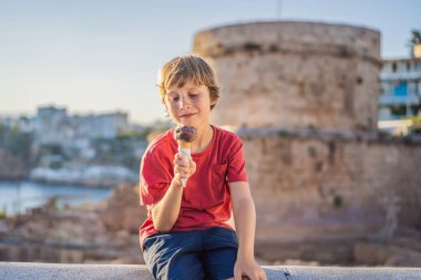 Antalya 'daki Hidirlik Kulesi' nin arka planında Türk dondurması yiyen çocuk turist, antik Kaleici ilçesinin Akdeniz Körfezi 'nin arka planına karşı. Türkiye.