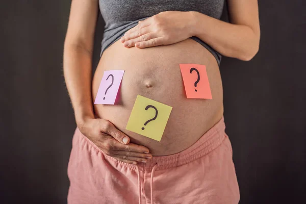 Väljer Babynamn Förvirrad Gravid Kvinna Med Frågetecken Papper Klistermärken Magen — Stockfoto