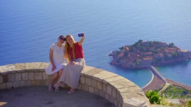 Karadağ 'daki Saint Sava kilisesi yakınlarında oturan iki genç kadının, uzaktaki Sveti Stefan adasının çarpıcı manzarasına hayran oldukları görülüyor. Kamera onların heyecanını yakalar.