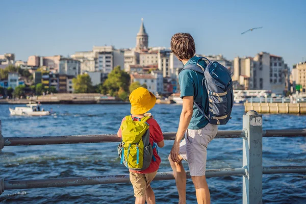 Baba ve oğul turistler Türkiye 'de İstanbul şehrinin ufuk çizgisinin keyfini çıkarırken, Beyoğlu' nda Galata kulesinin tepesinde eski evler, Altın Boynuz manzarası.