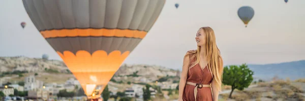 バナー トルコのカッパドキアで熱気球を見てロングフォーマット観光の女性 トルコのコンセプトでハッピートラベル 山頂の女が素晴らしい景色を楽しむ — ストック写真