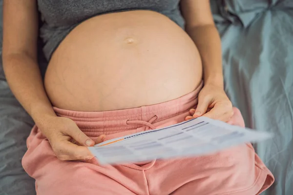 Μια Έγκυος Γυναίκα Εξετάζει Αποτελέσματα Μιας Εξέτασης Αίματος Τυπωμένη Χαρτί — Φωτογραφία Αρχείου