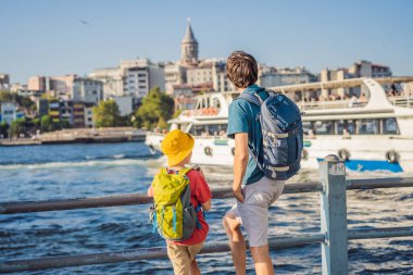 Baba ve oğul turistler Türkiye 'de İstanbul şehrinin ufuk çizgisinin keyfini çıkarırken, Beyoğlu' nda Galata kulesinin tepesinde eski evler, Altın Boynuz manzarası.