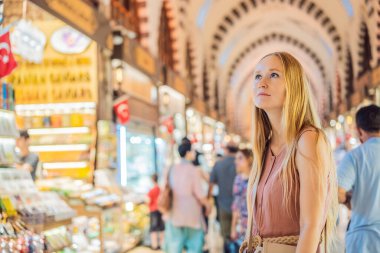 İstanbul 'daki Kapalıçarşı ve Mısır Çarşısı' ndaki sayısız dükkan arasında bir turist kadın yürüyor. Türkiye 'de alışveriş ve seyahat. İstanbul tarihi Mısır Çarşısı. Bayan Carsisi, baharat.