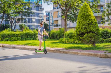 Şehirdeki arka planda elektrikli scooter kullanan genç bir adam. Kiralık elektrikli scooterlar..