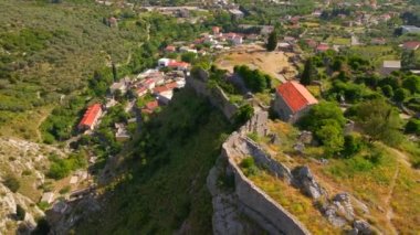 This aerial stock video captures the stunning ruins of the Old Bar or Stari Bar, a historical landmark in Montenegro. The drone footage showcases a birds eye view of a stone fortress and an aqueduct