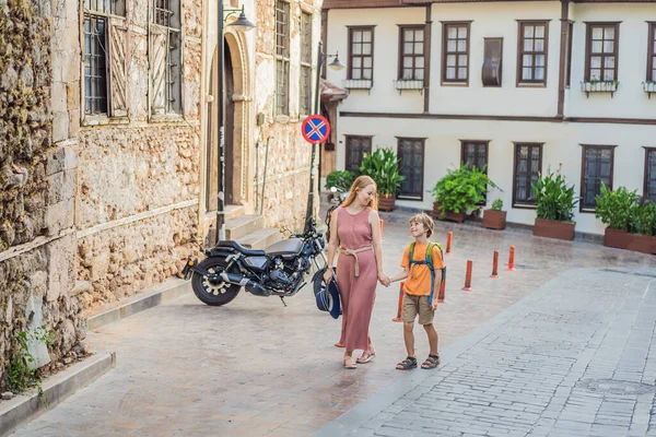 Mom and son tourists in Old town Kaleici in Antalya. Turkiye. Panoramic view of Antalya Old Town port, Taurus mountains and Mediterrranean Sea, Turkey. Traveling with kids concept.