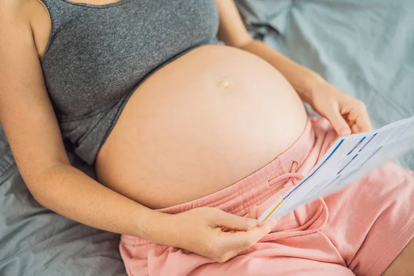 Μια Έγκυος Γυναίκα Εξετάζει Αποτελέσματα Μιας Εξέτασης Αίματος Τυπωμένη Χαρτί — Φωτογραφία Αρχείου