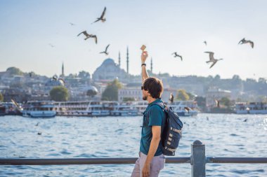Pembe elbiseli genç gezgin İstanbul 'da İstanbul Boğazı manzarası ve bir sürü martı seyrediyor..