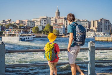 Baba ve oğul turistler Türkiye 'de İstanbul şehrinin ufuk çizgisinin keyfini çıkarırken, Beyoğlu' nda Galata kulesinin tepesinde eski evler, Altın Boynuz manzarası.