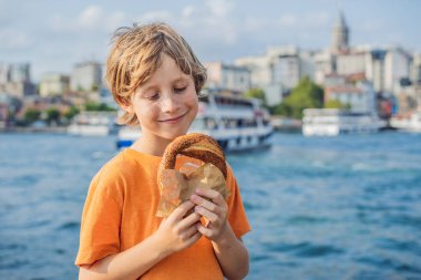 İstanbul 'da bir çocuk Simit ve bir bardak Türk çayı ile kahvaltı yapıyor. Altın boynuz koyuna ve İstanbul 'daki Galata Kulesi' ne karşı bir bardak Türk çayı ve simit Simit. Hindi. Birlikte seyahat etmek.