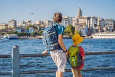 Baba ve oğul turistler Türkiye 'de İstanbul şehrinin ufuk çizgisinin keyfini çıkarırken, Beyoğlu' nda Galata kulesinin tepesinde eski evler, Altın Boynuz manzarası.