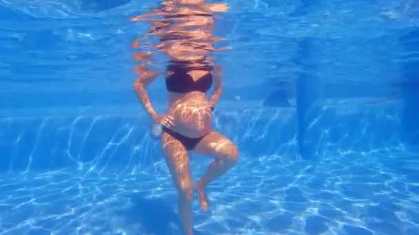 この水中ビデオでは 妊婦がスイミングプールで水の練習をしているのが見られます 彼女の赤ちゃんのバンプで 彼女はの利点を実証し 水の中で簡単に移動します — ストック動画