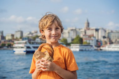 İstanbul 'da bir çocuk Simit ve bir bardak Türk çayı ile kahvaltı yapıyor. Altın boynuz koyuna ve İstanbul 'daki Galata Kulesi' ne karşı bir bardak Türk çayı ve simit Simit. Hindi. Birlikte seyahat etmek.