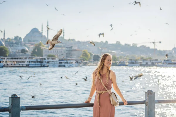 Pembe elbiseli genç bayan gezgin İstanbul 'da İstanbul Boğazı manzarası ve bir sürü martı seyrediyor..