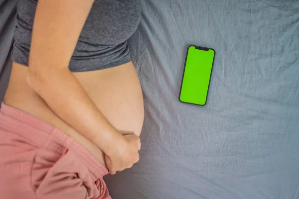 Pregnant girl with a smartphone. The concept of a negative impact on the unborn child in the womb. Violation of the nervous system of the child, reproductive.