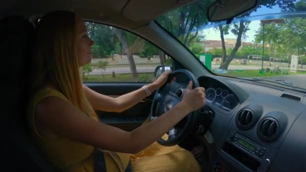 黄色のドレスを着た妊婦は 美しい周囲を通り過ぎる景色の良い道路で車を運転しています スローモーションビデオ — ストック動画