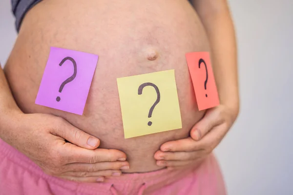 Väljer Babynamn Förvirrad Gravid Kvinna Med Frågetecken Papper Klistermärken Magen — Stockfoto