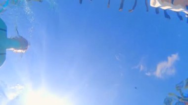 Bu yavaş çekim sualtı videosunda, hamile bir kadın yüzme havuzunda kameranın üzerinde yüzüyor.