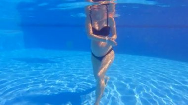 Bu yavaş çekim sualtı videosunda, hamile bir kadın yüzme havuzunda su egzersizleri yaparken görülüyor. Bebek çarpmasıyla, suyun içinde rahatça hareket ediyor, bunun faydalarını gösteriyor.