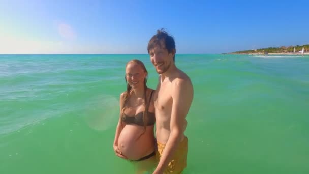 一段慢镜头拍摄了一名孕妇和一名男子在热带海域快乐探险的场景 他们手牵着手走着 用一个自拍的视频用一个行动摄像头捕捉他们的假日记忆 — 图库视频影像