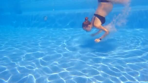 水中でのスローモーションビデオでは 妊娠中の女性が優雅さと流動性を持ってスイミングプールに飛び込みます 水の中に降りていくと 光が肌を覆い 永遠の効果を生み出します — ストック動画