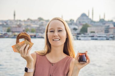 İstanbul 'da Simit ve bir bardak Türk çayıyla kahvaltı yapan bir kadın. İstanbul, Türkiye 'de altın boynuz koyuna karşı bir bardak Türk çayı ve simit Simit. Türkiye.