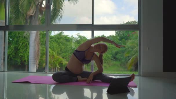 在这个视频中 可以看到一个年轻的孕妇在她的公寓里做瑜伽练习 背景是全景窗和茂密的热带背景 缓慢而优雅 — 图库视频影像