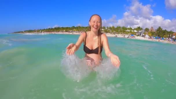 熱帯の海で楽しんでいる妊婦のスローモーションビデオ 彼女はカメラに水を撒いている — ストック動画