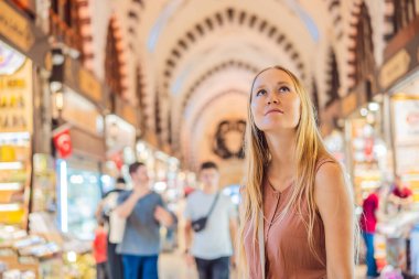 İstanbul 'daki Kapalıçarşı ve Mısır Çarşısı' ndaki sayısız dükkan arasında bir turist kadın yürüyor. Türkiye 'de alışveriş ve seyahat. İstanbul tarihi Mısır Çarşısı. Bayan Carsisi, baharat.