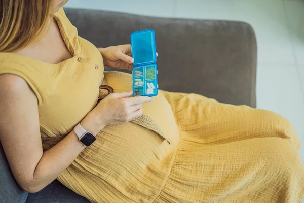 出生前のビタミン 自宅でソファに座っている間に健康的な妊娠のためのサプリメントを取りながら 美しい笑顔妊娠中の女性の肖像画 フリースペース — ストック写真