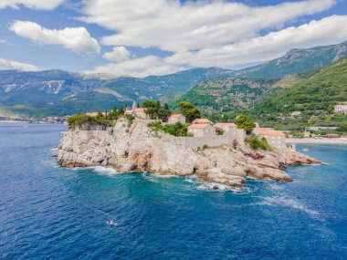 Genç kadınlar, Karadağ 'ın St. Stefan adası yakınlarındaki mavi denizde ayakta kürek çekerken eğleniyorlar. Çeviri:.