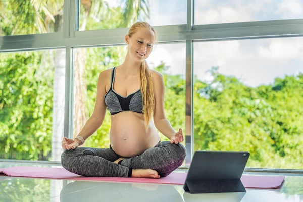 昼間に屋内でオンラインビデオレッスンでマットでヨガをしている若い妊婦の肖像画 バランスの練習 健康管理 スポーツライフスタイル フィットネス ウェルネス 妊娠の概念 — ストック写真