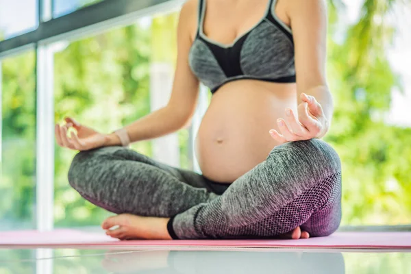 stock image Young pregnant woman doing yoga exercises and meditating at home or yoga studio. Health care, mindfulness, relaxation and wellness concept.