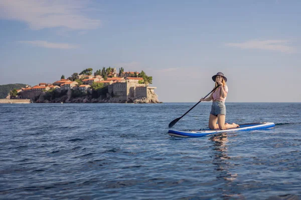在黑山圣斯特凡岛附近的蓝色海面上 年轻女人有一个有趣的站起来的垫子 Sup — 图库照片