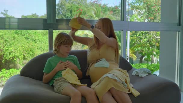心温まるストックビデオは 妊娠中の母親と彼女の長男が居心地の良いソファーに座って 興奮と期待に満ちた貴重な瞬間をキャプチャします 彼らはAを介してブラウズ — ストック動画