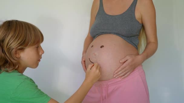 Küçük Bir Çocuk Hamile Annesinin Karnına Gülümseyen Bir Yüz Çiziyor — Stok video