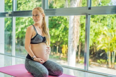 Genç hamile kadın yoga egzersizleri yapıyor ve evde veya yoga stüdyosunda meditasyon yapıyor. Sağlık, farkındalık, rahatlama ve sağIık kavramı.