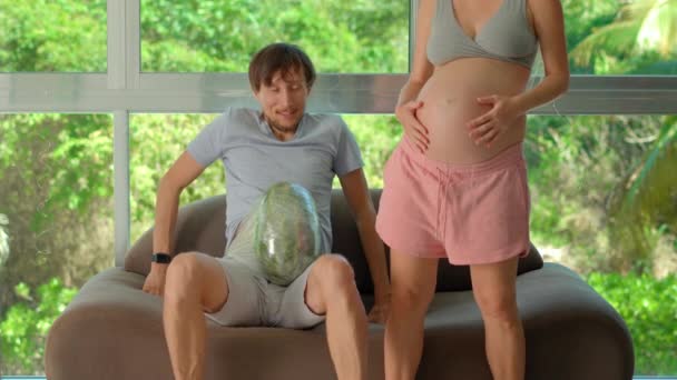 在这个幽默的慢动作视频中 一个孕妇开玩笑地把西瓜绑在她丈夫的肚子上 对怀孕的重量和经历进行了轻松的模拟 她教他怎么做 — 图库视频影像