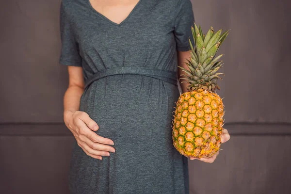 妊娠中の女性の腹は パイナップルに似た赤ちゃんの大きさを美しく示しています 妊娠と出産中にパイナップルの潜在的な利点と害を探索する — ストック写真