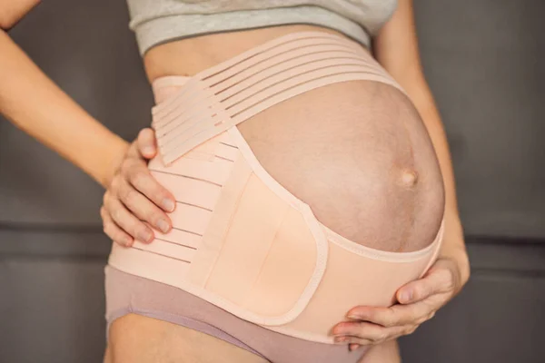 安全でサポートされていると感じている妊婦は 優しいサポートと快適さを提供するために妊娠のために設計された包帯を着用します — ストック写真