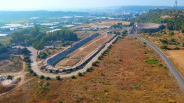 Hava videosu. İnsansız hava aracı, Türkiye 'nin Antalya kentindeki antik Perge kentinin kalıntılarında hipodromun üzerinde uçuyor. Bu görüntüler Antalyas tarihine benzersiz bir bakış açısı sunuyor