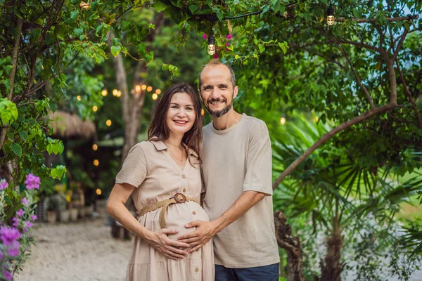 A blissful scene in the park as a radiant pregnant woman after 40 and her loving husband after 40, cherish the joy of parenthood together, surrounded by natures serenity.