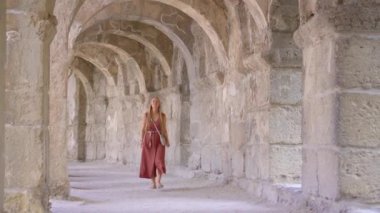 Genç bir kadın turist antik Roma tiyatrosu Aspendos 'un sütunlu galerisinin içinde yürüyor. Türkiye kavramına yolculuk.