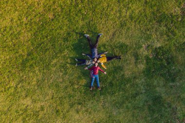 Aile manzarası. Çimlerin üzerinde yatıyordu. Güneşli bir gün. Yeşil doğada birlikte. Hava görüntüleme Drone fotoğrafçılığı.