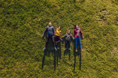 Aile manzarası. Çimlerin üzerinde yatıyordu. Güneşli bir gün. Yeşil doğada birlikte. Hava görüntüleme Drone fotoğrafçılığı.